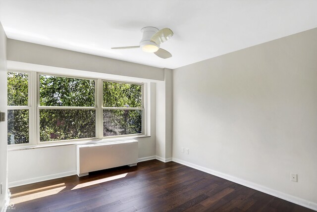 empty room featuring ceiling fan, dark hardwood / wood-style flooring, and radiator