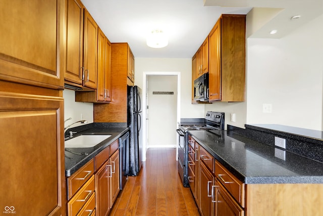 kitchen featuring sink, dark stone countertops, black appliances, and hardwood / wood-style floors