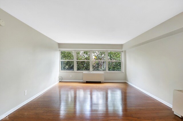 spare room featuring hardwood / wood-style floors and radiator heating unit