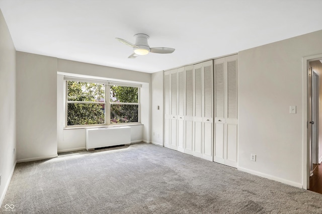 unfurnished bedroom with carpet floors, ceiling fan, a closet, and radiator