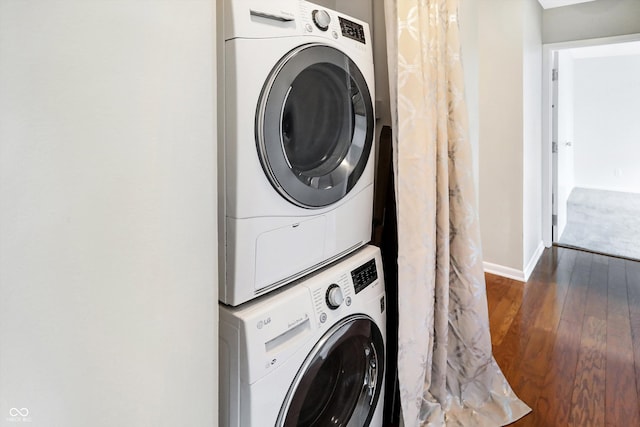 clothes washing area with stacked washer / drying machine and dark hardwood / wood-style floors