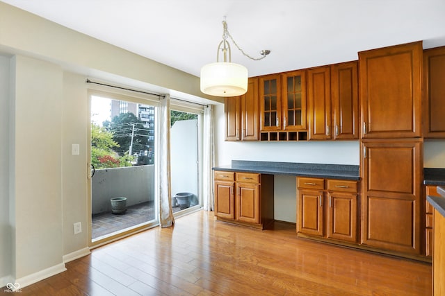 kitchen with light hardwood / wood-style floors, built in desk, and hanging light fixtures