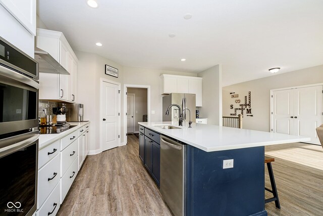 kitchen featuring white cabinetry, sink, stainless steel appliances, and a spacious island