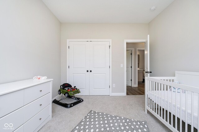 bedroom with a crib, carpet, and a closet