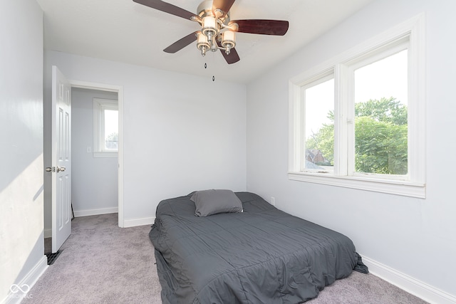 carpeted bedroom featuring multiple windows and ceiling fan