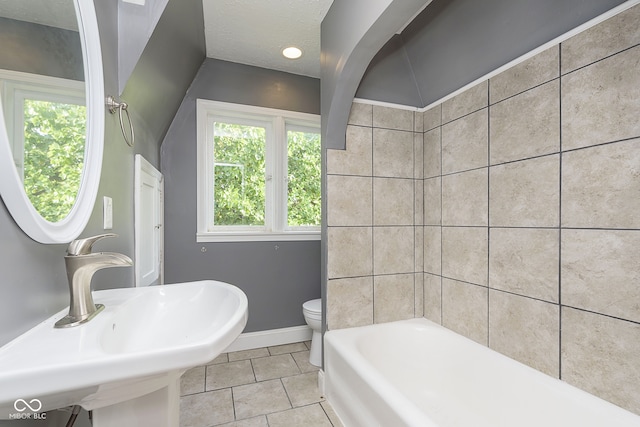 bathroom featuring toilet, tile patterned floors, a textured ceiling, sink, and a bath