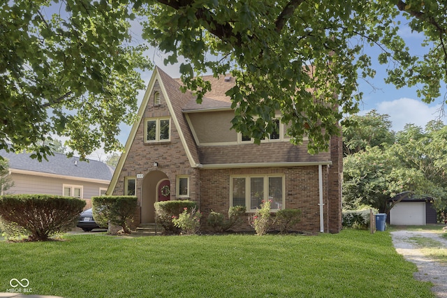 english style home featuring an outbuilding, a garage, and a front lawn