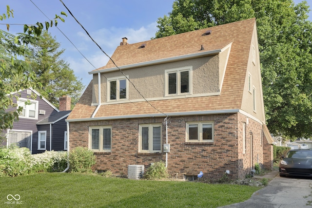 rear view of property with central air condition unit and a lawn