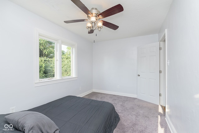 bedroom with a textured ceiling, ceiling fan, and carpet