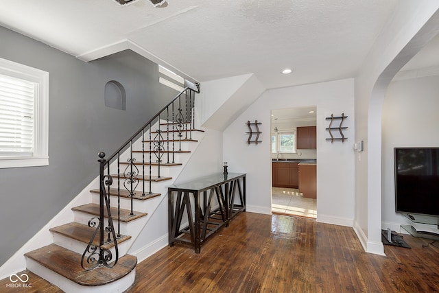 stairs with a textured ceiling, wood-type flooring, and sink