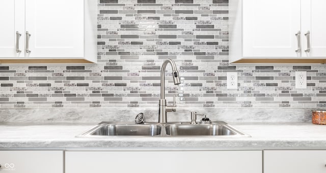 kitchen featuring light countertops, decorative backsplash, a sink, and white cabinets