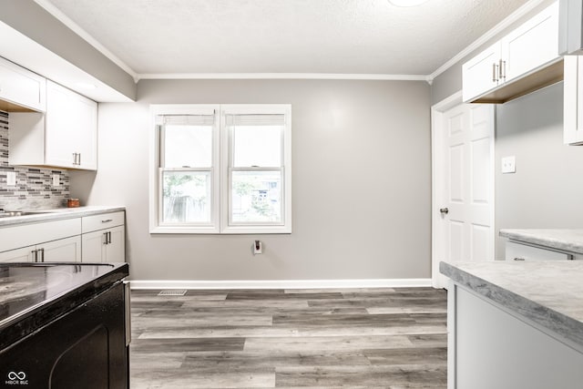 kitchen featuring ornamental molding, light countertops, white cabinets, and wood finished floors