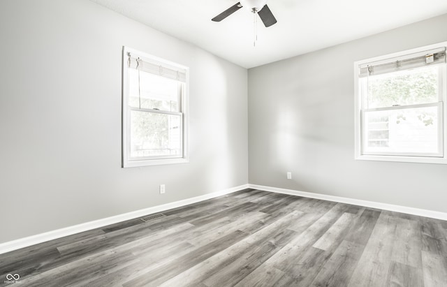 empty room with hardwood / wood-style flooring, a healthy amount of sunlight, and ceiling fan