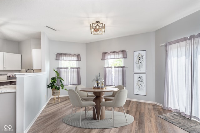 dining space with wood finished floors, visible vents, and baseboards