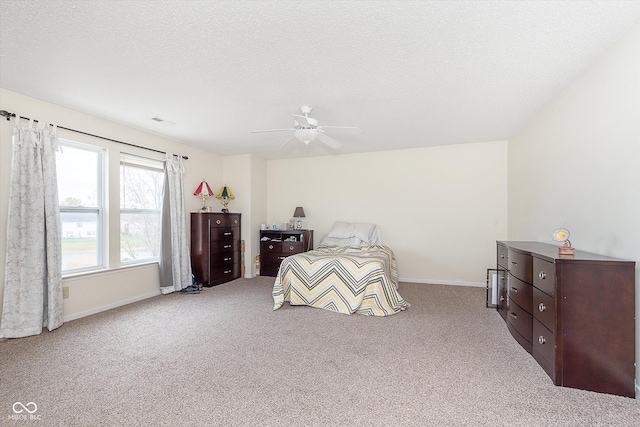 bedroom with a textured ceiling, carpet floors, ceiling fan, and baseboards