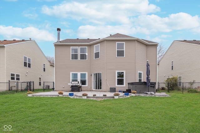 back of property featuring a patio area, a lawn, a hot tub, and a fenced backyard