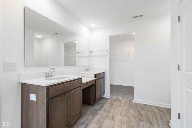 bathroom featuring vanity, a walk in closet, visible vents, and baseboards