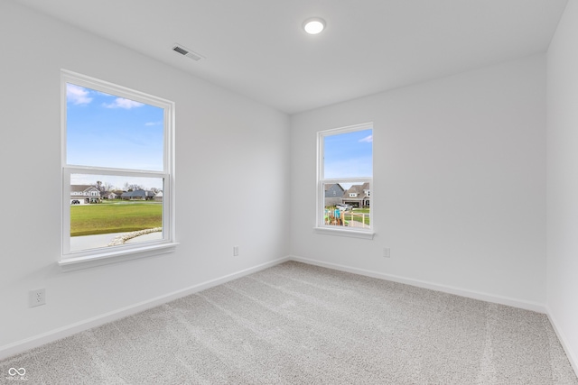 unfurnished room with carpet, visible vents, and baseboards