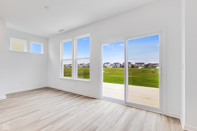 interior space featuring light wood-type flooring, baseboards, a residential view, and visible vents