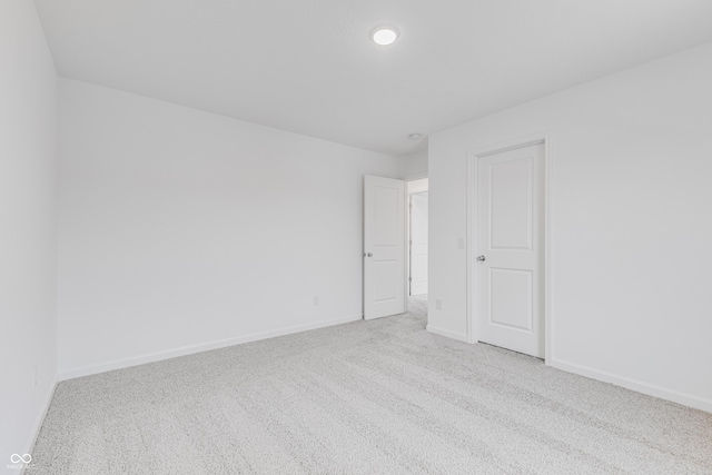 unfurnished room featuring baseboards and light carpet