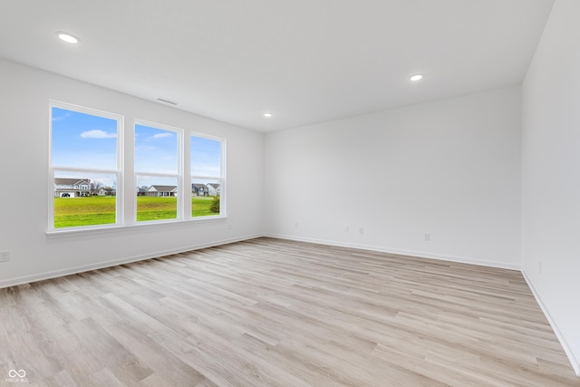 empty room featuring baseboards, light wood-type flooring, and recessed lighting