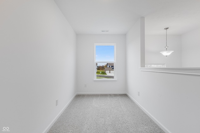 spare room with carpet flooring, visible vents, and baseboards