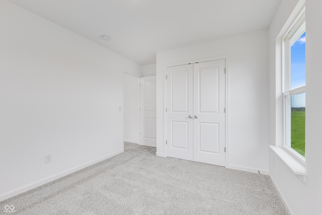 unfurnished bedroom with baseboards, a closet, and light colored carpet