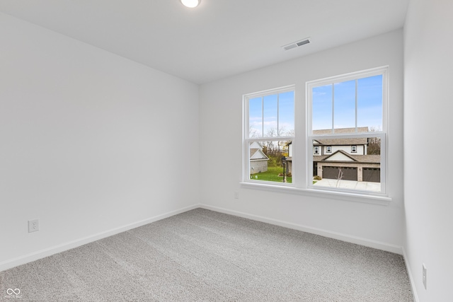 empty room with baseboards, visible vents, and carpet flooring