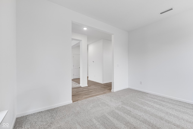 spare room with baseboards, visible vents, and light colored carpet