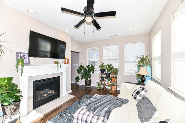 living room featuring ceiling fan, a high end fireplace, and dark hardwood / wood-style flooring