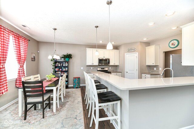 kitchen with tasteful backsplash, decorative light fixtures, a kitchen bar, and stainless steel appliances