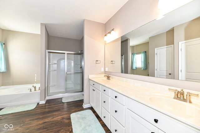 bathroom with hardwood / wood-style flooring, separate shower and tub, and double vanity