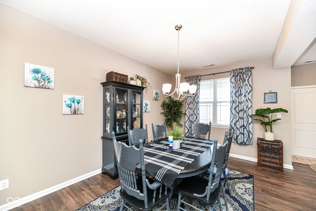 dining room with dark wood-type flooring and a notable chandelier