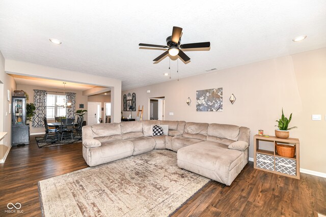 living room featuring ceiling fan with notable chandelier, a textured ceiling, and dark hardwood / wood-style flooring