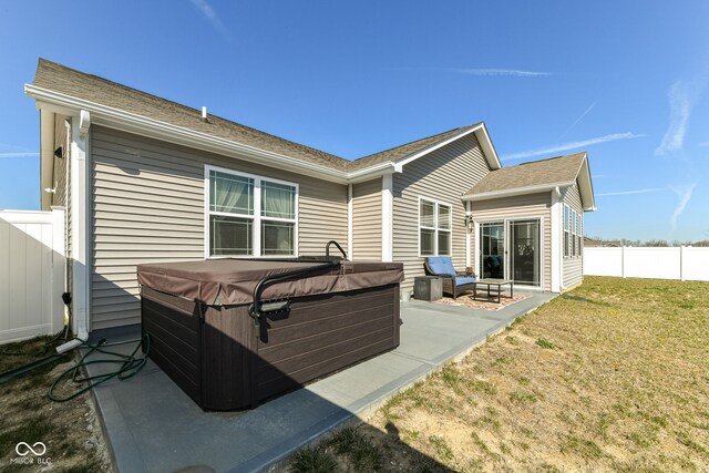 rear view of property featuring a patio area, a lawn, and a hot tub