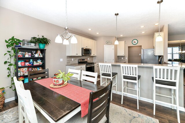 dining area with sink, a chandelier, and wood-type flooring