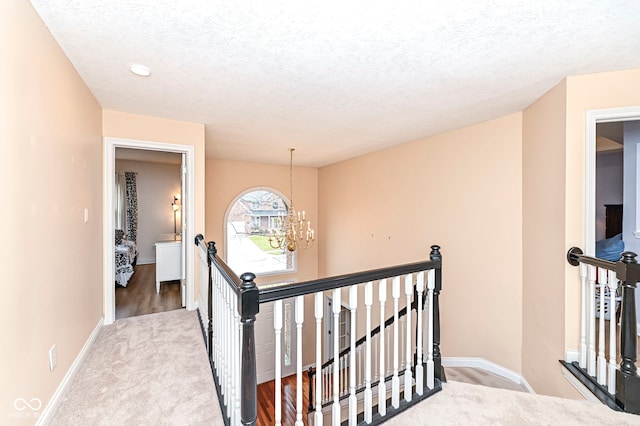 14626 Warner Trl, Westfield, IN 46074 - hall with an upstairs landing, a chandelier, carpet floors, baseboards, and a textured ceiling