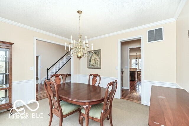 14626 Warner Trl, Westfield, IN 46074 - dining area with a chandelier, ornamental molding, stairway, a textured ceiling, and light colored carpet