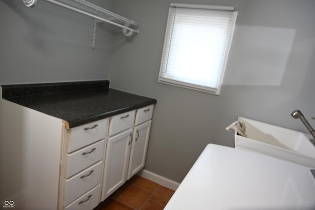 clothes washing area with laundry area, dark tile patterned floors, and baseboards