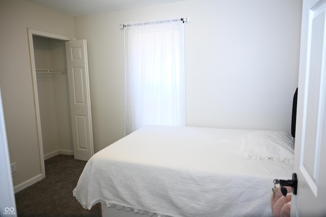 bedroom with dark colored carpet, a closet, and baseboards