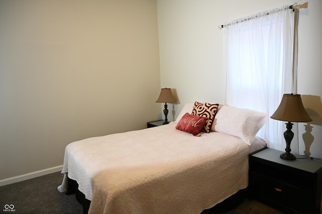 bedroom with dark colored carpet and baseboards