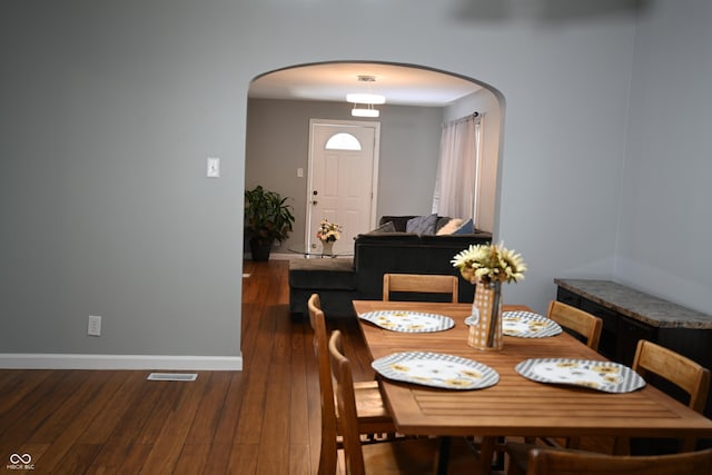 dining area with dark wood-style floors, baseboards, and arched walkways