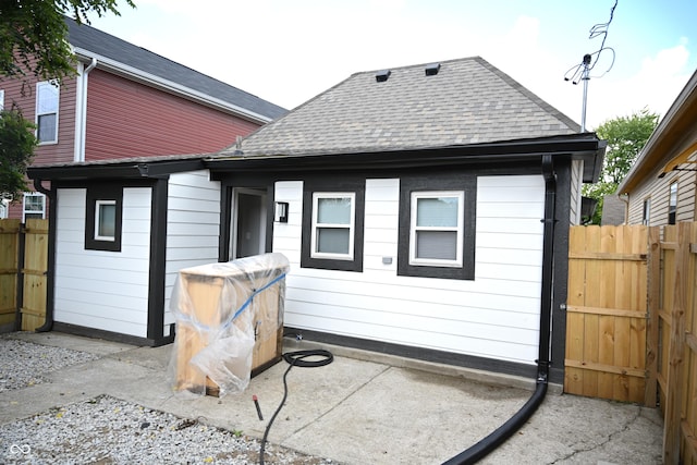 back of property with roof with shingles, a patio area, and fence