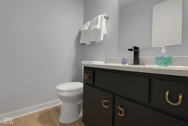 bathroom featuring wood-type flooring, vanity, and toilet