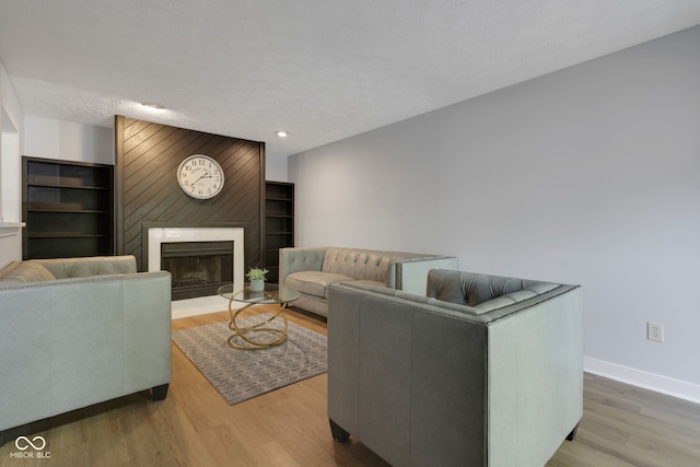 living room with a large fireplace, light hardwood / wood-style floors, and a textured ceiling