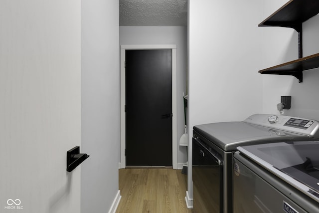 washroom with separate washer and dryer, a textured ceiling, and light wood-type flooring