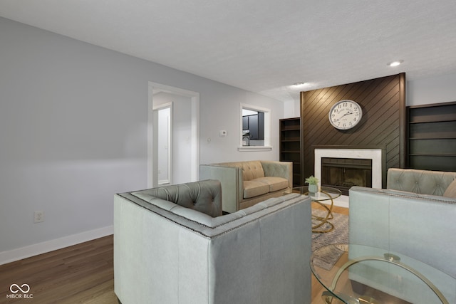 living room with a textured ceiling, wood-type flooring, and a large fireplace