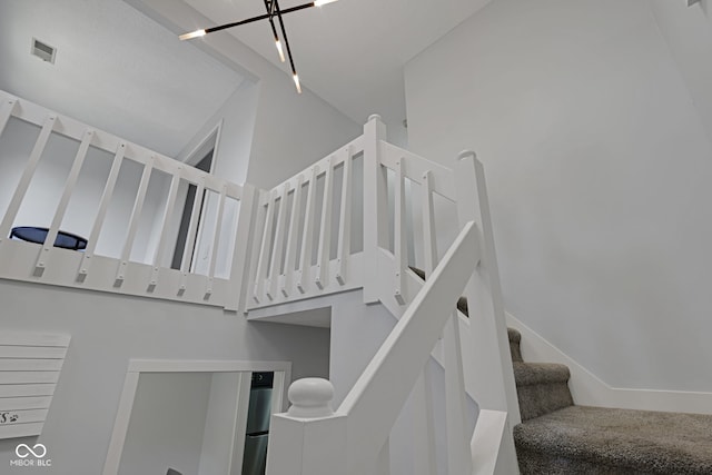 staircase with a towering ceiling and rail lighting