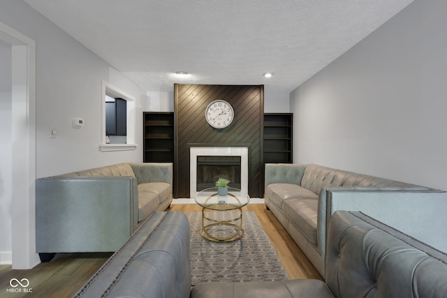 living room with a textured ceiling, a fireplace, and hardwood / wood-style floors