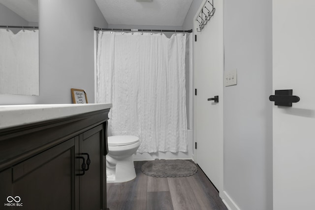 bathroom with wood-type flooring, vanity, toilet, and a textured ceiling